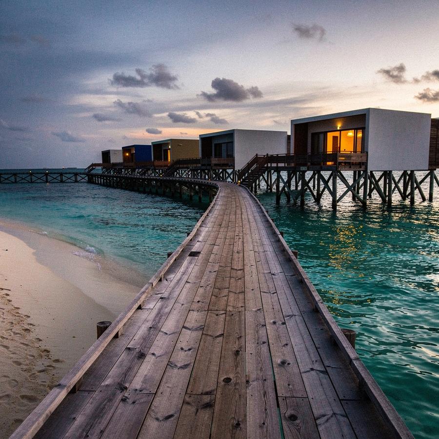 Overwater villas above a Maldives reef at dusk